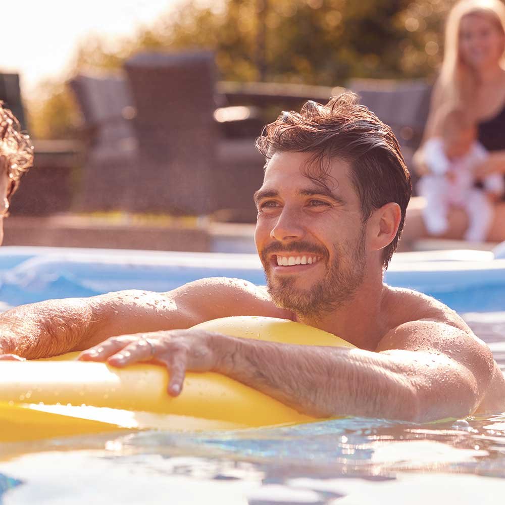 Hombre jugando con niño en pileta